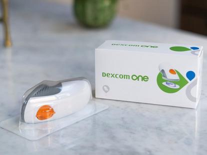 "Dexcom ONE" jutiklis ir dėžutė ant stalo